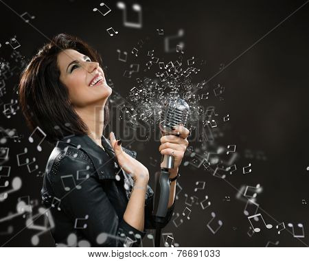 Half-length portrait of female rock musician keeping sounding mic on dark grey background