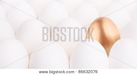gold Easter egg between many white eggs