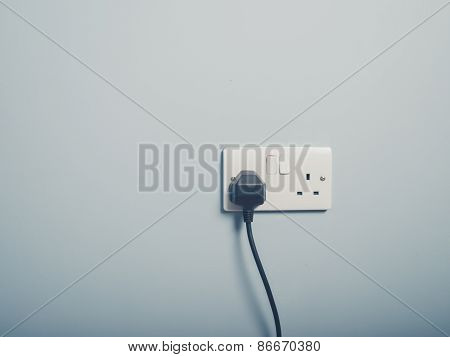 Uk Wall Socket And Cord On Blue Wall
