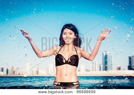 Woman on city beach splashing water drops
