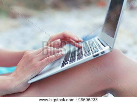 Image of girls hands typing on the beach. Selective focus