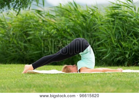 Young Woman Practicing Yoga Halasana Plow Pose