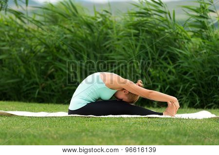 Woman Practicing Yoga In The Park Seated Forward Bend
