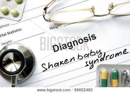 Diagnosis Shaken baby syndrome and tablets on a wooden table.