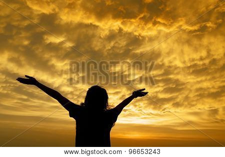 Silhouette Of A Girl Spreading Hand Toward The Clouds