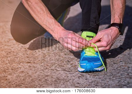 Athlete during training tying shoelaces on sneakers summer.
