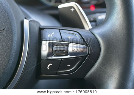 Hands free and media control buttons on the steering wheel in black leather modern car interior