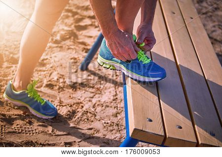 Athlete during training tying shoelaces on sneakers summer.