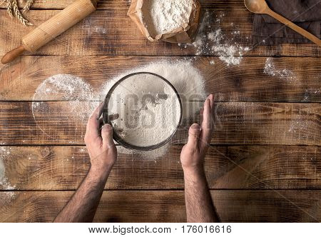 Man sifted flour on the wooden table top view