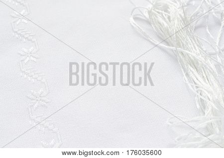 Texture of linen fabric with embroidery by flat stitch white silk. Macro handmade embroidery.
