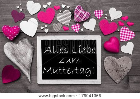 Chalkboard With German Text Alles Liebe Zum Muttertag Means Happy Mothers Day. Pink Textile Hearts. Grey Wooden Background With Vintage, Or Retro Style. Black And White Style With Colored Hot Spots
