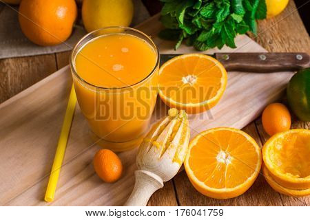 Citrus fruits oranges lemons lime cumquat fresh mint reamer freshly pressed juice in glass on wood kitchen table by window top view