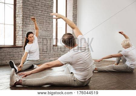 Feel this exertion. Photo of healthy people wearing comfortable clothes sitting on the floor while doing yoga