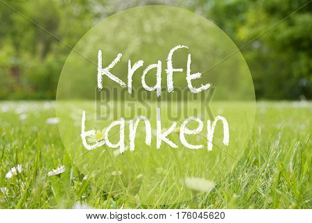 German Text Kraft Tanken Means Relax. Spring Or Summer Gras Meadow With Daisy Flowers. Blurry Trees As Background.