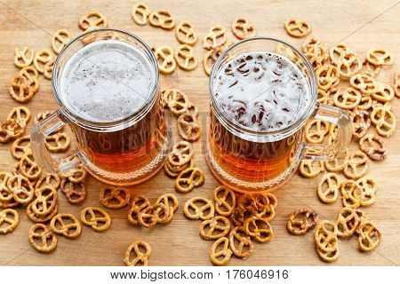 Mug of cold foamy beer with brezel. Overhead view. Traditional german Oktoberfest snacks and beer on wooden background