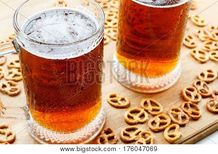 Mug of cold foamy beer with brezel. Traditional german Oktoberfest snacks and beer on wooden background