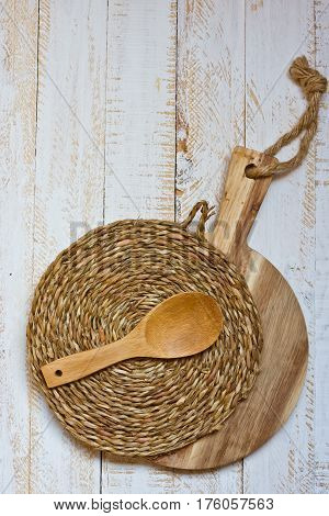 Wood round cutting board and wicker rattan coaster spoon on white plank wood background rustic kitchen interior Provence style minimalistic kinfolk