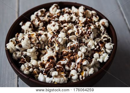 a bowl with chocolate popcorn on wood