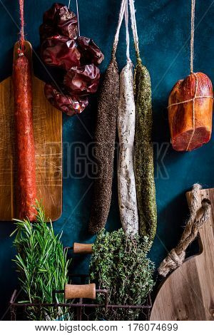 Assortment of sausages Spanish charcuterie wood cutting board fresh garden herbs on dark blue background gourmet