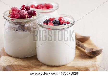 Homemade yogurt with frozen berries red currants black currants raspberries and cranberries in three banks