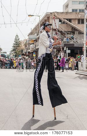 Participants At сarnival On Stilts Are Walking Along The Street