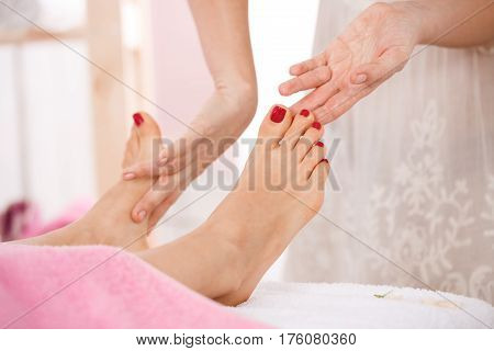 Close up of woman feet with red nailpolish getting relazing foot massage at spa salon