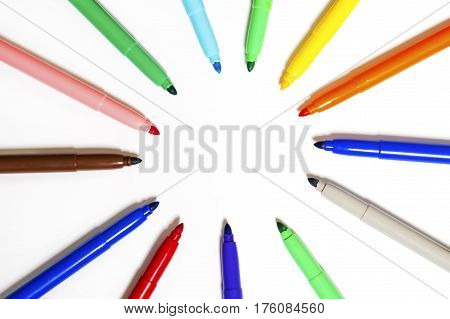 Colored marker pens lie around on white paper