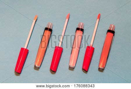Three lip gloss bottles on blue background