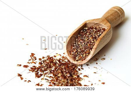 Ground flax seeds in wooden scoop on light background