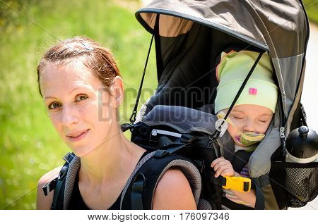 Mother With Baby In Backpack Carrier Is Hiking In Mountains.