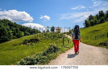 Father with baby in backpack carrier is hiking in mountains. Tourist is carrying a child on his back in the nature of Slovenia.