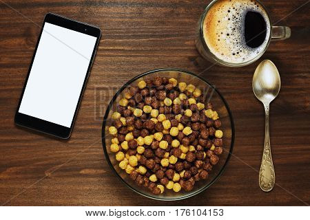 Browsing in the web with a cell phone or tablet while having simple breakfast of corn flakes and coffee