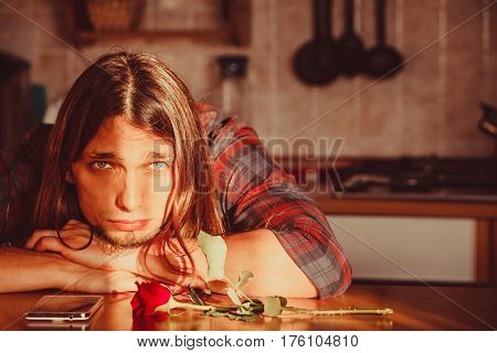 Disappointment and depression. Unrequited love concept. Young worried disappointed man with single red rose and smartphone mobile phone waiting for his girlfriend.