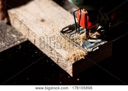 Close up photo of cutting wood with fretsaw over dark background. Copy space.