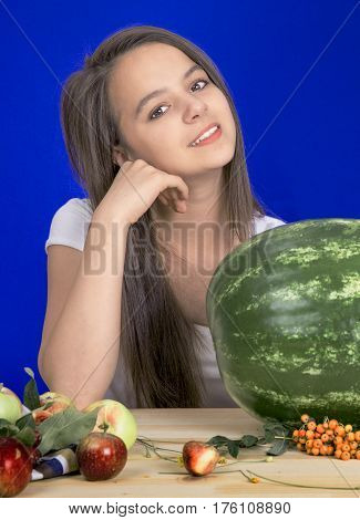 The smiling girl with the whole big water-melon on a blue background