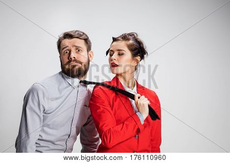 The funny business man and woman cooperating on a gray background. Business concept of leadership of colleagues