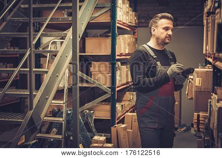 Storekeeper with mobile computer working in a warehouse.