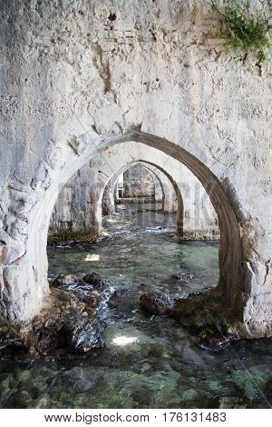 Arches made of stone inside shipyard of Alanay medieval castle built in XIII century by Alaeddin Keykubat with turquoise water