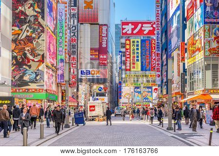 TOKYO, JAPAN - JANUARY 11, 2017: Crowds pass below colorful signs in Akihabara. The historic district electronics has evolved into the shopping area for video games, anime, manga, and computer goods.