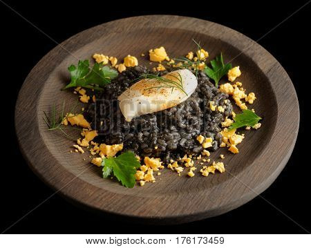 Black rice cooked with cuttlefish ink, and fried calamar, isolated on black background