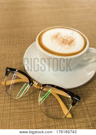 A cup of coffee with glasses put on the wooden table