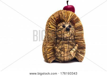 Handmade hedgehog made of hay with artificial apple isolated on white background