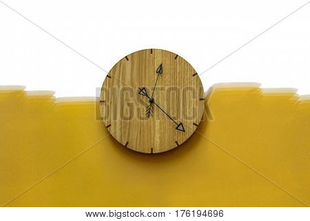 Wood clock hanging on white and yellow wall almost half past twelve