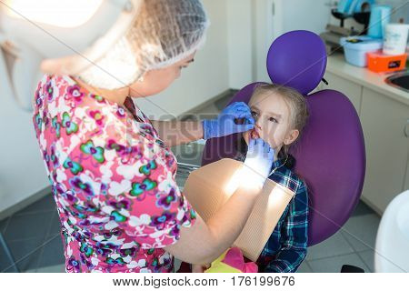 Child as patient with female dentist during dental intervention in dental clinic