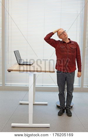 middle age balding man relaxing neck - short break for exercise on chair in office
