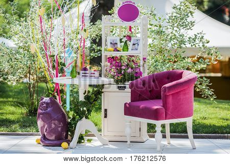 Beautiful unusual wedding decor. Photo zone with whatnot, armchair, table and cat sculpture