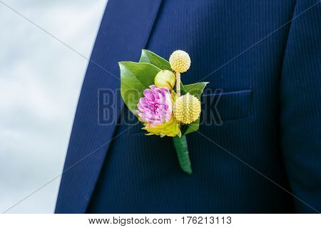 Pink peon boutonniere pinned to a grooms blue jacket