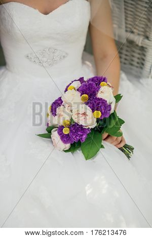 Bride holding delicate and tender marriage bouquet in purple and pink colours with green petals