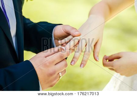 Newlyweds staying arm in arm, with wedding rings, closeup