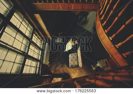 Wedding Couple Sits On The Old Sofa Behind A Big Window